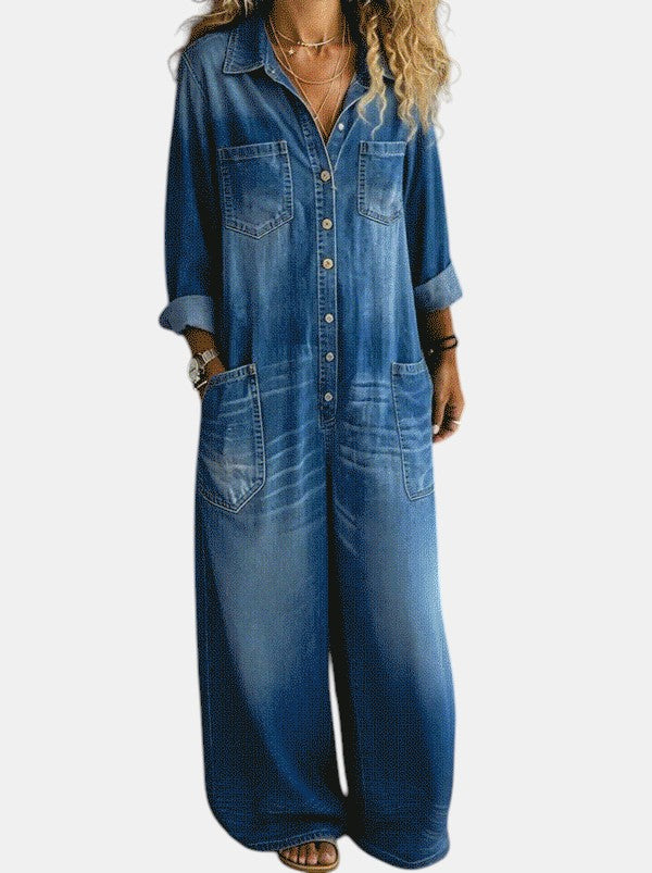 Mulher vestindo macacão jeans Emma Genève azul de corte largo, mangas compridas dobradas e bolsos frontais.