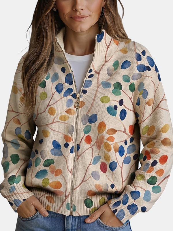 Cardigan Emma Genève Consuelo em malha creme com estampado de folhas coloridas, fecho de correr dourado e corte bomber.