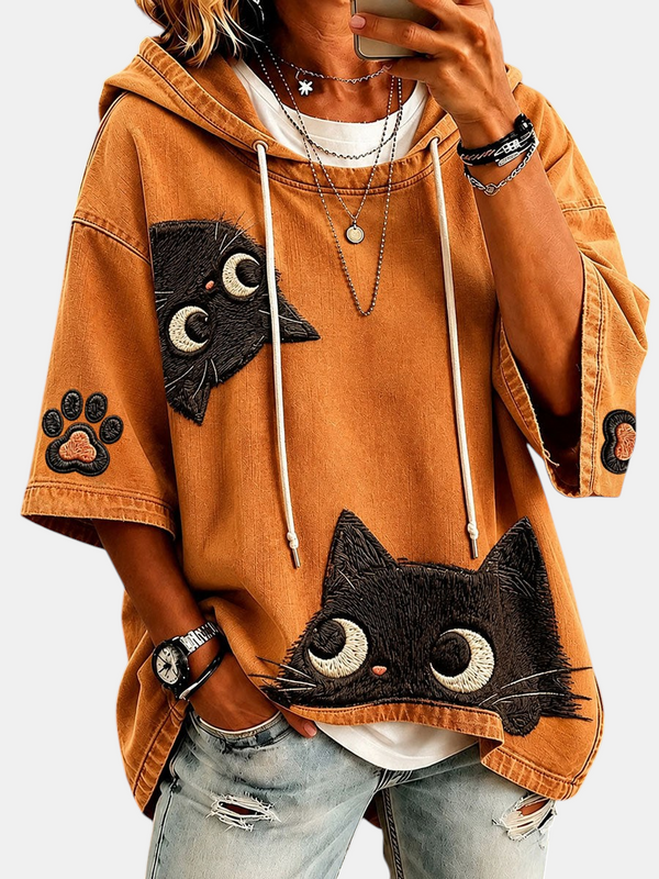 Sweat à capuche Emma Genève ocre, manches mi-longues et écussons brodés de chats noirs, en mélange de coton.